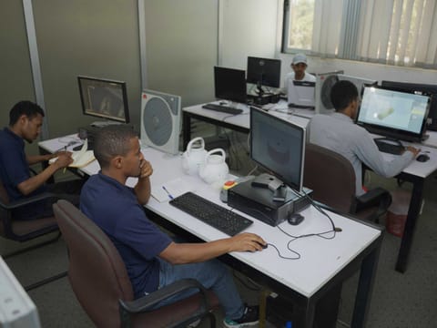 An engineer at a CAD workstation with moulded plastic product samples on the desk