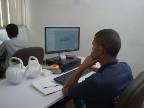 An engineer studying a 3D CAD model of a component on a monitor