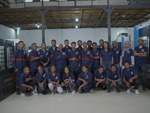 Group photograph of the ZG Industrial Automation team in branded work uniforms inside the factory hall