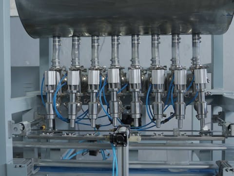 Multi-head linear liquid filling machine with stainless steel filling nozzles