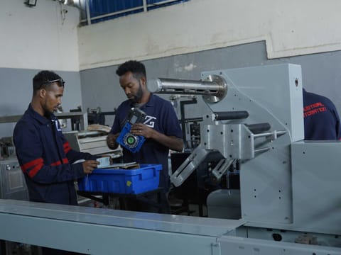 Technicians loading a film roll onto a horizontal flow wrapping machine