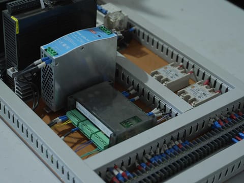 Control cabinet interior with power supply unit and PLC terminal blocks on DIN rail