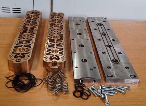 Machined mould plates laid out with springs, bolts and seals ready for assembly