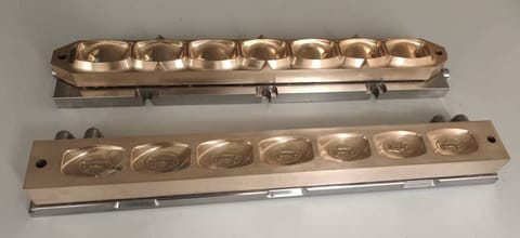 Rows of brass soap mould cavities with engraved detail